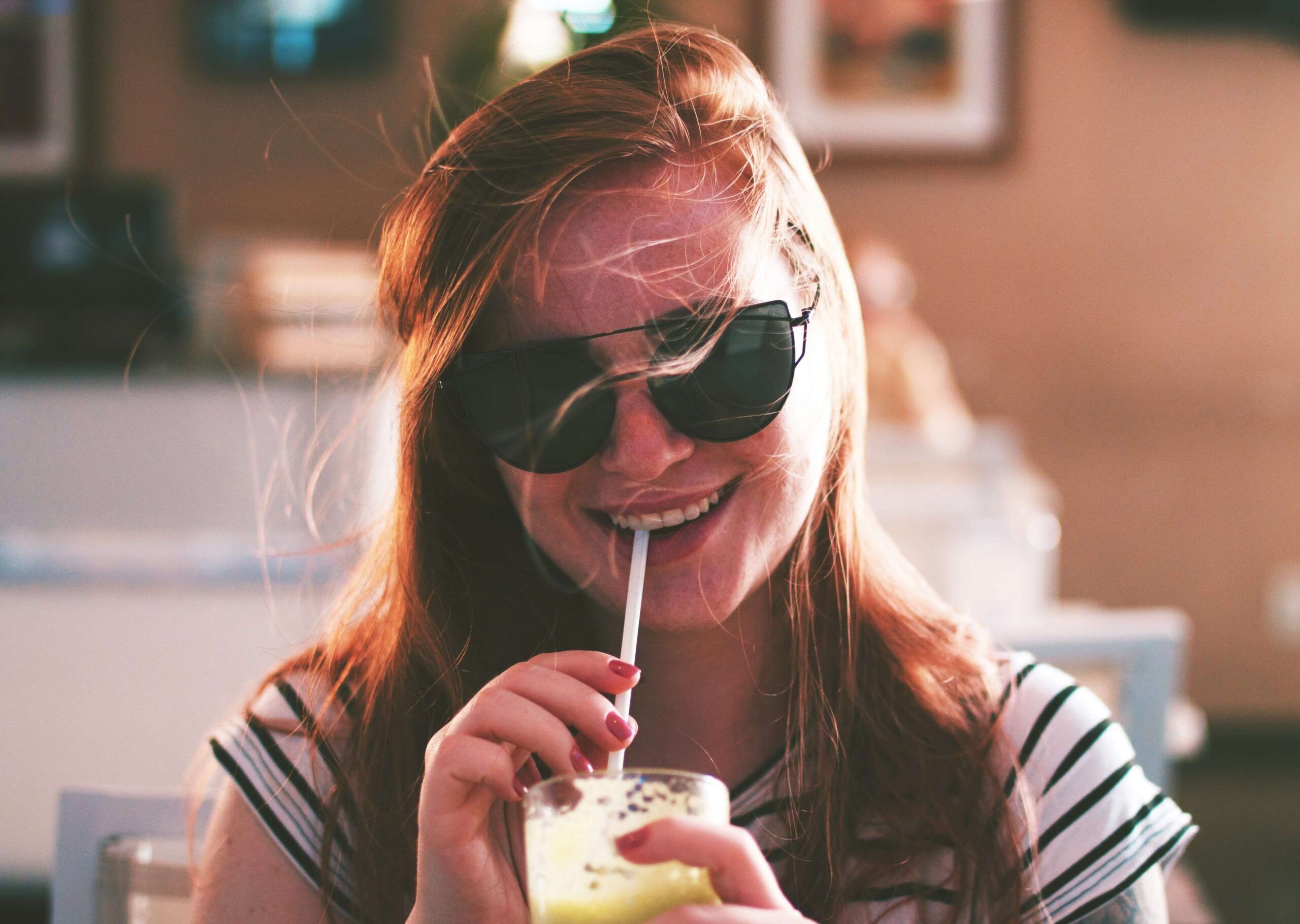 An individual wearing sunglasses smiling while drinking from a straw. Our disordered eating therapy in Asheville, NC can support your recovery journey. Call us today to learn more.