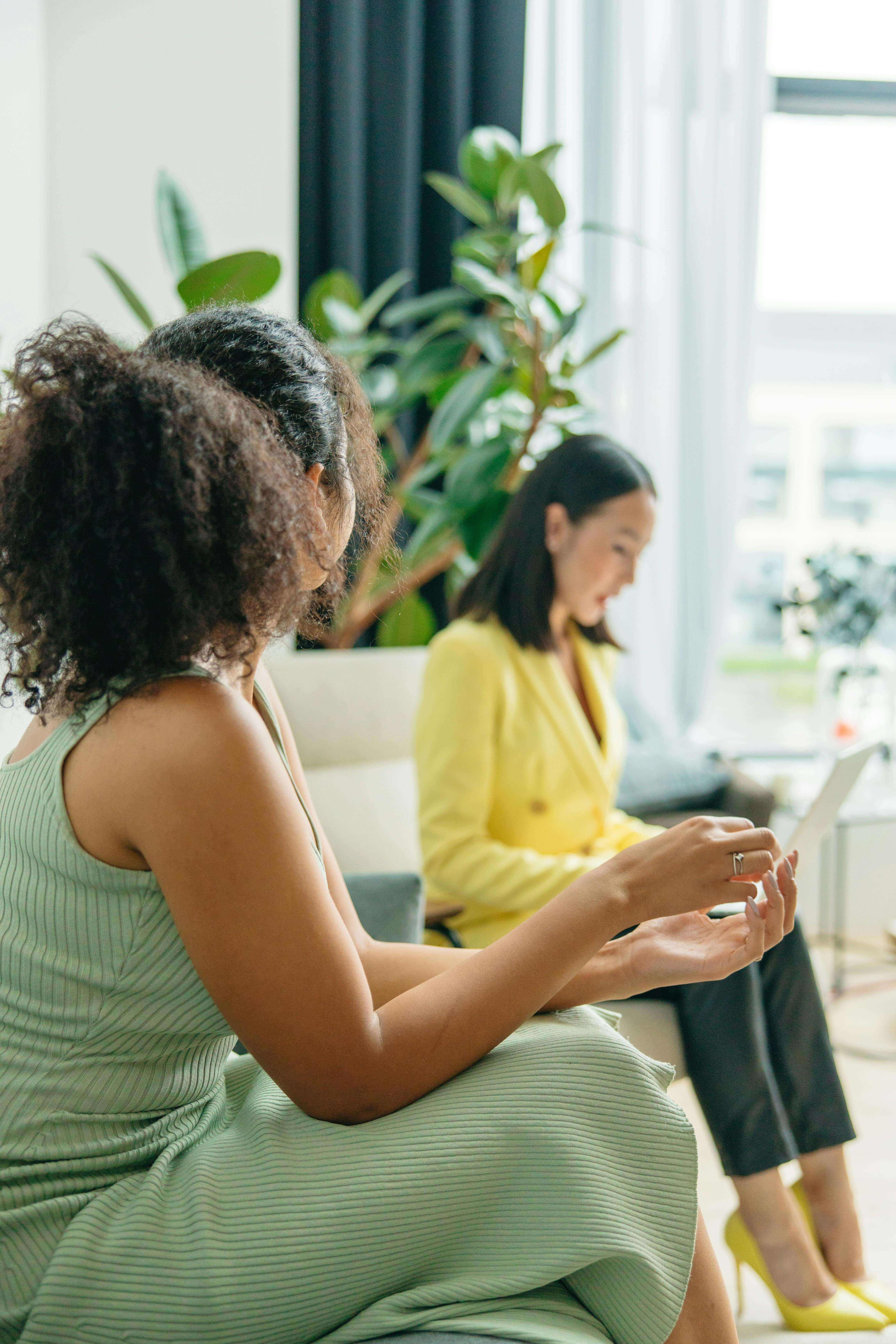 A client in a green dress engages in a discussion during a nutritional counseling session in Raleigh, NC, while a nutritionist in Asheville, NC takes notes on a laptop in a bright, welcoming office.