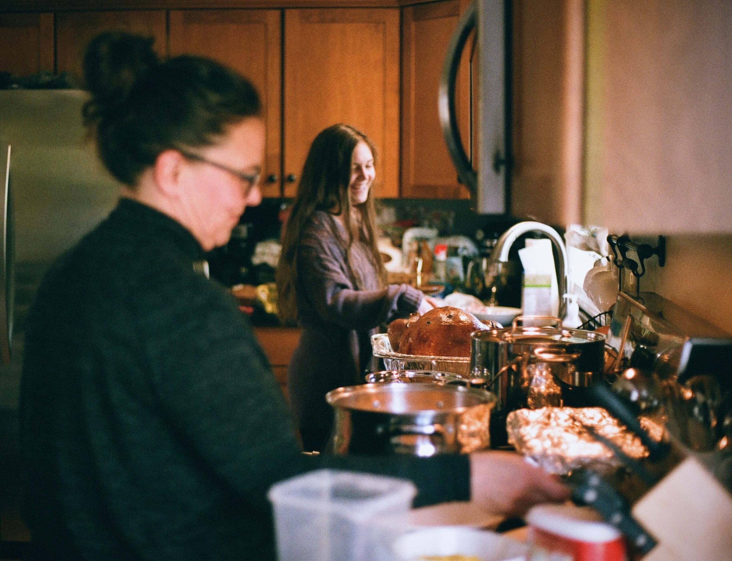 Two women cooking together while talking in the kitchen. Want to learn more about nutritional counseling in Raleigh, NC? Call us today to learn more!