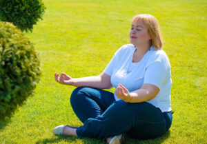 A woman meditating in a green grass field. Discover how a registered dietitian in Raleigh, NC can enhance your healing journey. Read our blog here for more information. 