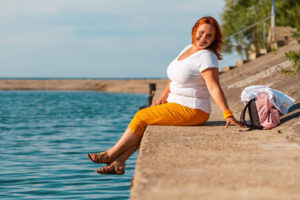 A woman wearing a white top & yellow pants posing by the water. Discover how medical nutrition therapy in Asheville, NC can help you manage disordered eating, chronic conditions & more. Get started with a dietitian today.