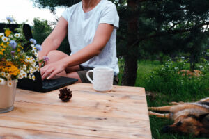 An individual sitting outside while typing on their laptop. Representing how our dietitians in Hendersonville, NC can provide online nutrition therapy. Reach out today to learn more!