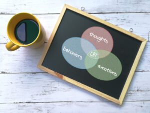 A whiteboard that reads "Thoughts, behaviors emotions" in circles near a coffe mug. CBT is one technique that we use in nutrition therapy. To learn more, reach out to a dietitian in Raleigh, NC. 