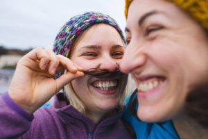 A happy lesbian couple smiling together. If you're looking for a nutritionist in Asheville, NC & surrounding areas, look no further! Call us today to start your healing journey.