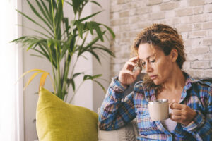 A woman putting her head down while drinking coffee. Nutritional therapy in North Carolina can help with disordered eating, trauma & more. Call us today to begin your healing journey. 