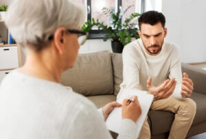 An individual sitting on a couch talking to a nutritional therapist. To get started with a nutritionist in Asheville, NC, reach out to us today. We can help support your recovery journey. 