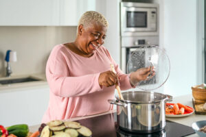 A woman stirring food in a large pot on the stove. Representing how our medical nutrition therapy in Cary, NC can help with diabetes management. Start working with our registered dietitians today.