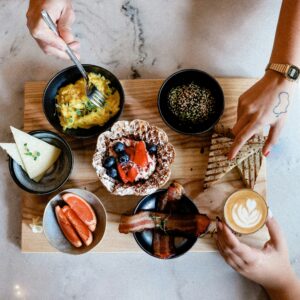 A platter with different breakfast foods separated by black bowls & individual hands reaching for food. Did you know nutritional counseling in Raleigh, NC can help with disordered eating? Reach out today to get started with a registered dietitian. 